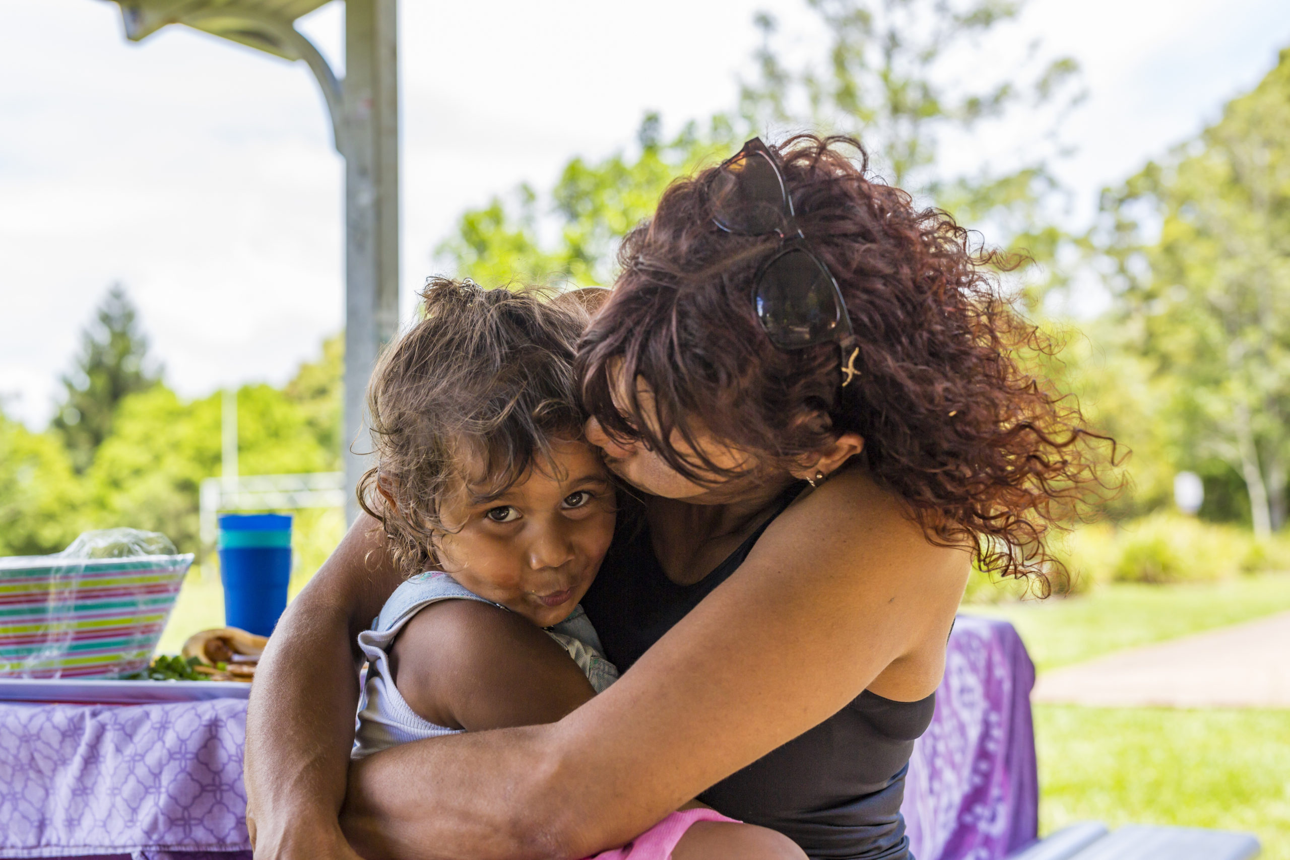 Australian Aboriginal woman giving her granddaughter a hug in the park